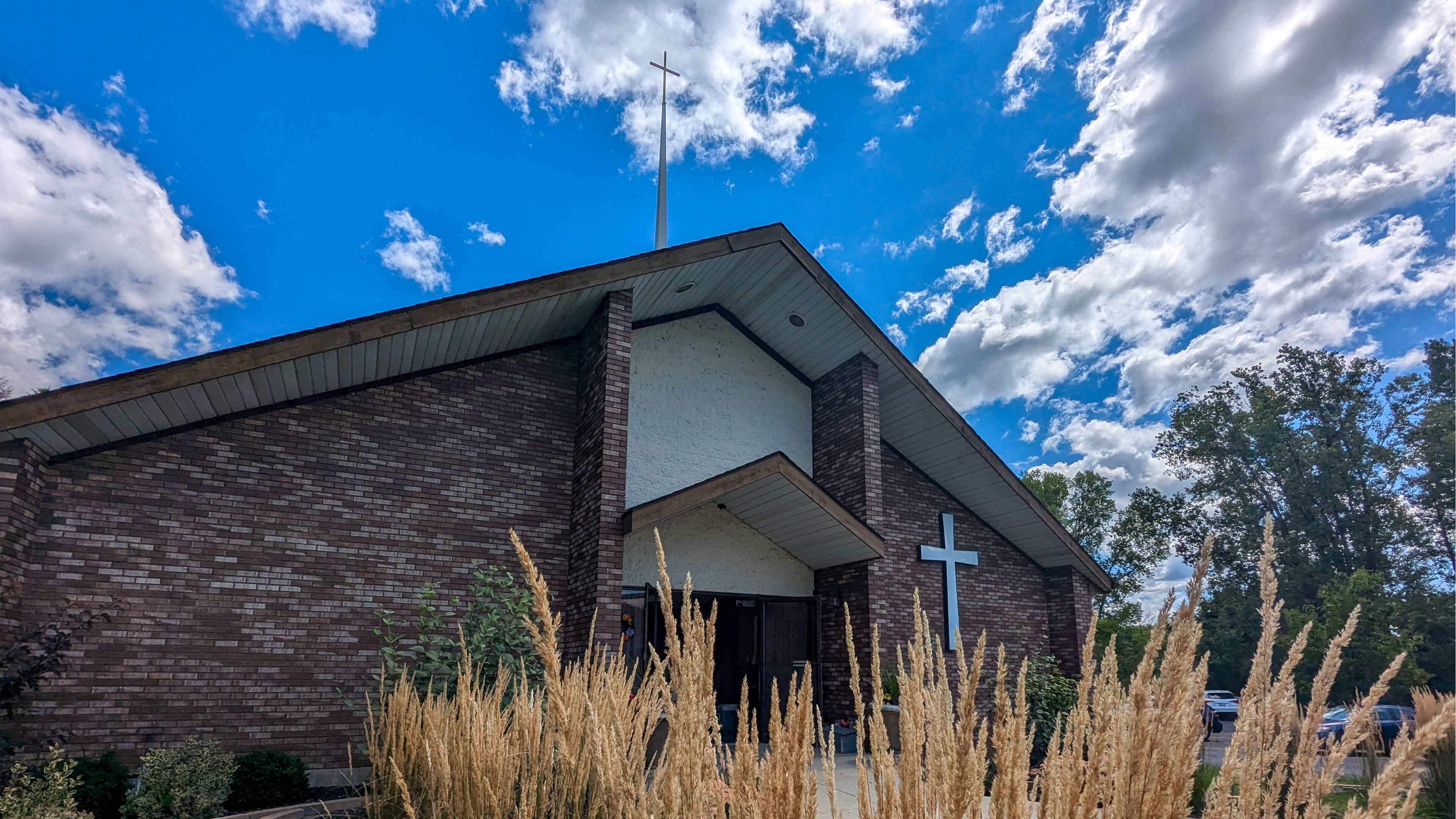 The stipel of Lamb of God Lutheran Church appears to pierce through the puffy clouds on a beautiful summer day.